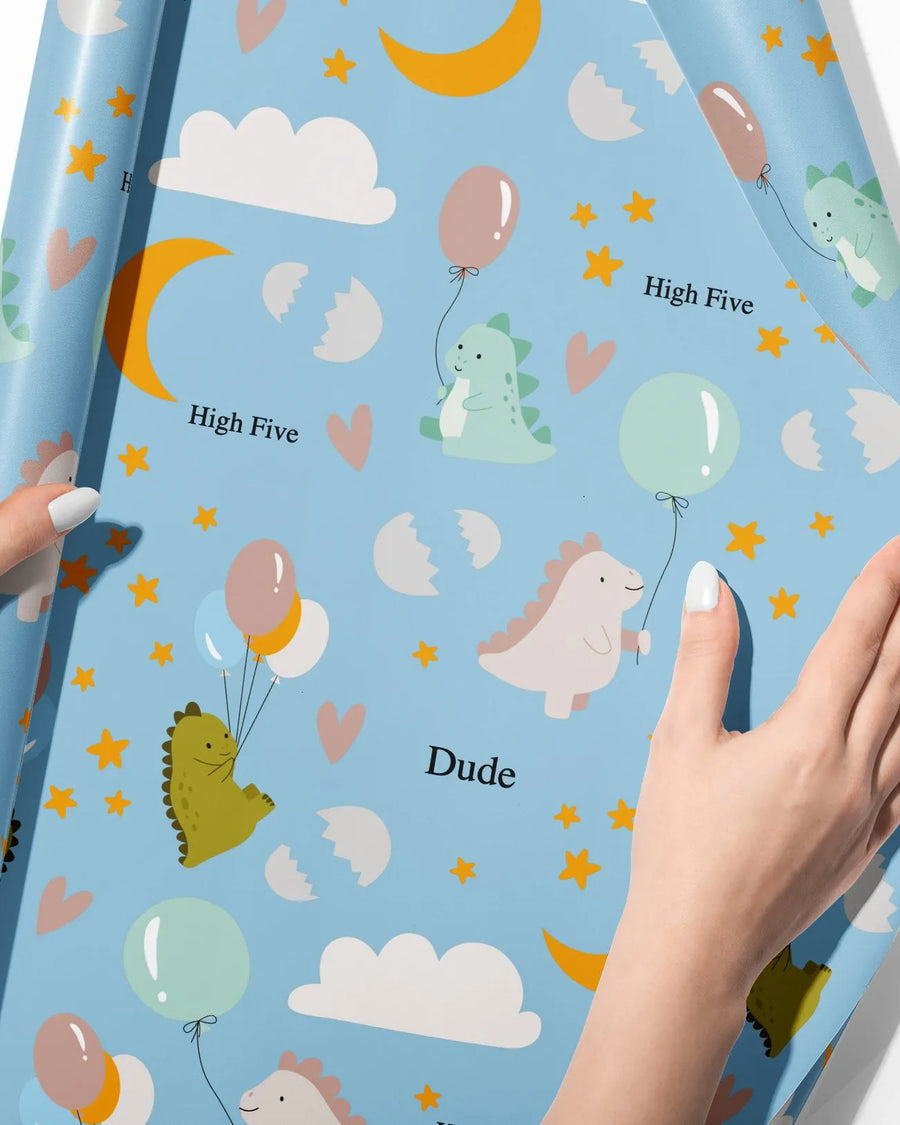Welcome baby dinosaur wrapping paper on a gift