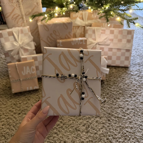 Name-printed gifts stacked under a Christmas tree